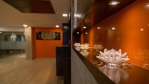 A reception area with a wooden floor and a wall-mounted display case containing decorative items. - Ginger Ahmedabad, Satellite (Ahmedabad)