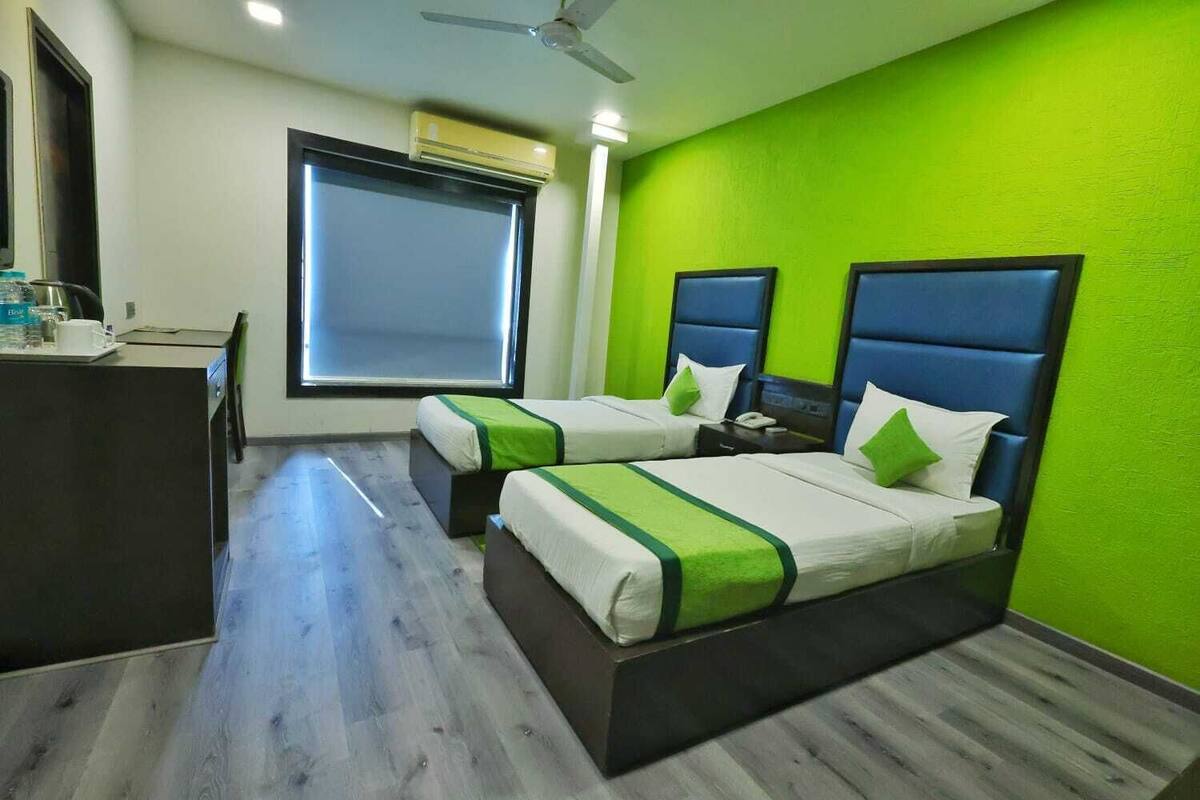 Una habitación de hotel con dos camas, un escritorio y un ventanal.