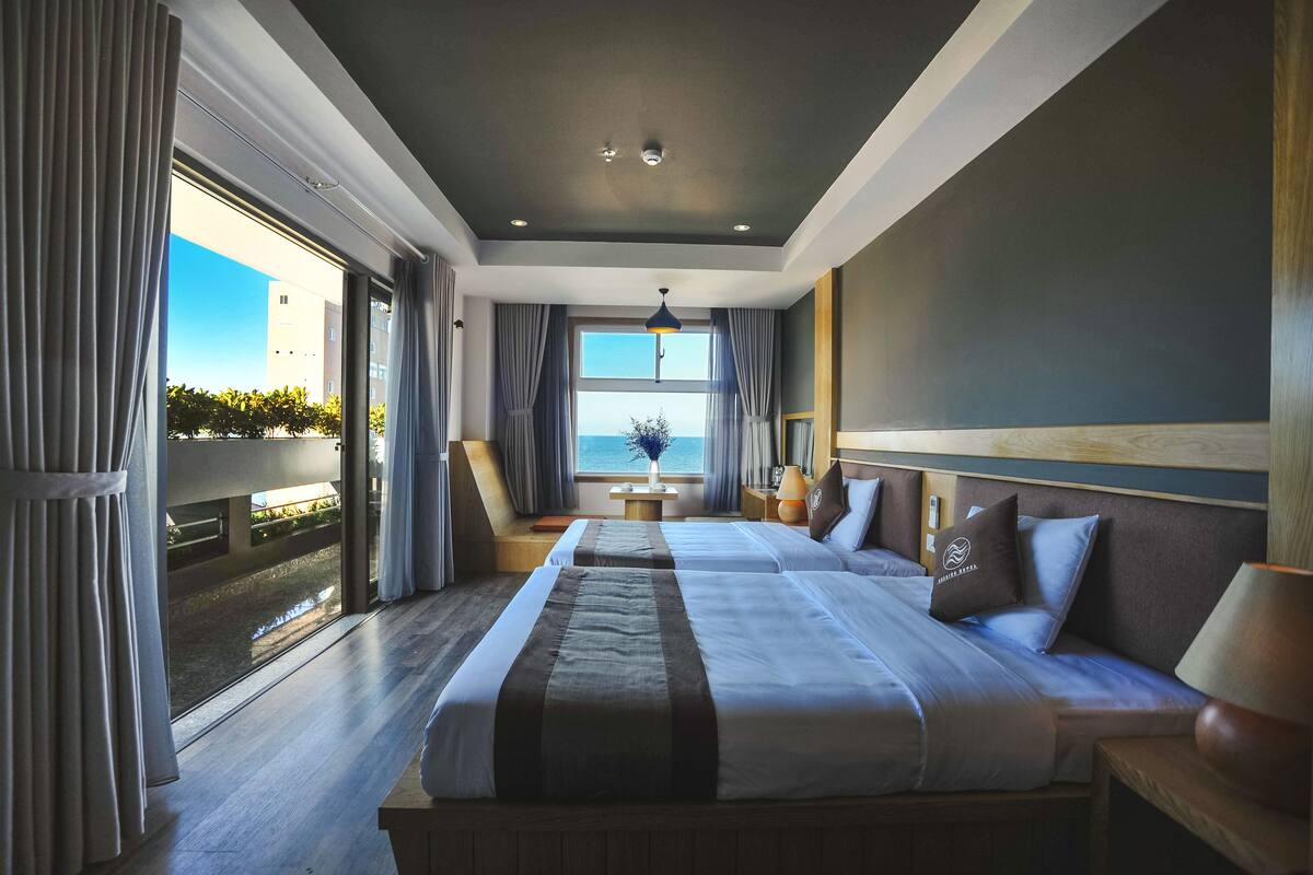 Une chambre d’hôtel avec un grand lit, une vue sur la mer et un balcon.