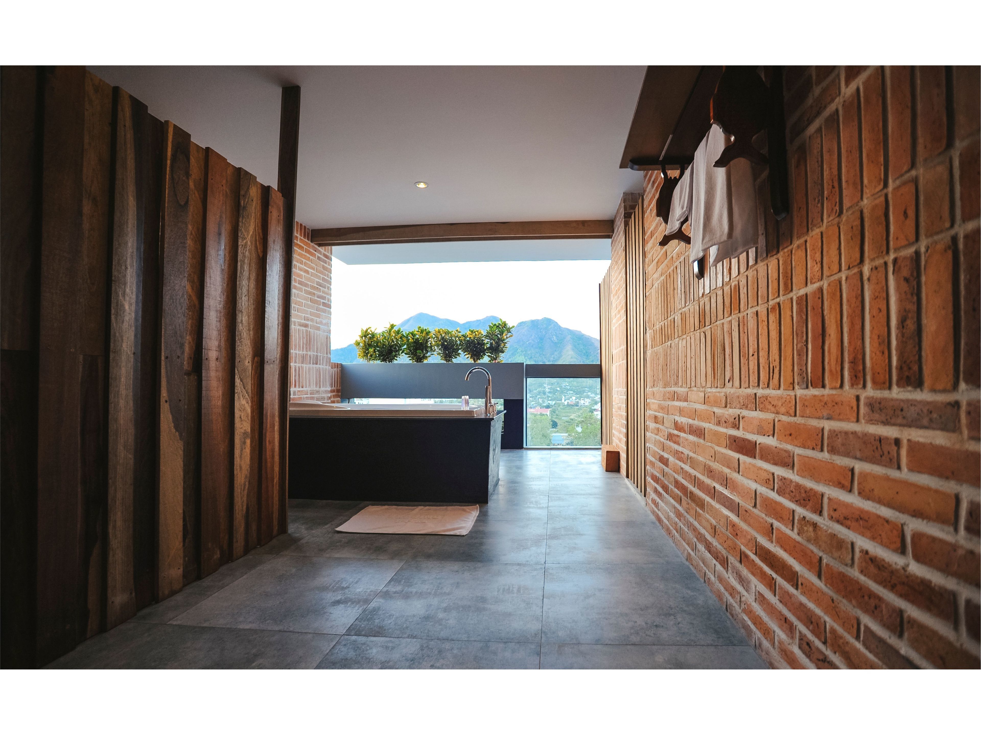A narrow hallway with a modern bathroom featuring a bathtub, a sink, and a large window offering a view of mountains.