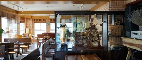A restaurant with wooden furniture, brick walls, and a glass partition.