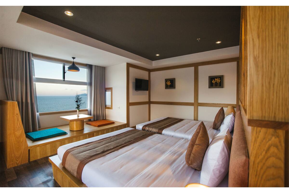 Une chambre d’hôtel avec un grand lit, un bureau, une chaise, une télévision et une vue sur la mer.