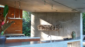 A modern kitchen with a concrete countertop, a built-in sink, and pendant lighting. - Umah Tampih Villa (Ubud)