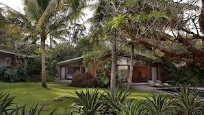 A modern house with a well-maintained garden, including palm trees and various plants. - Umah Tampih Villa (Ubud)