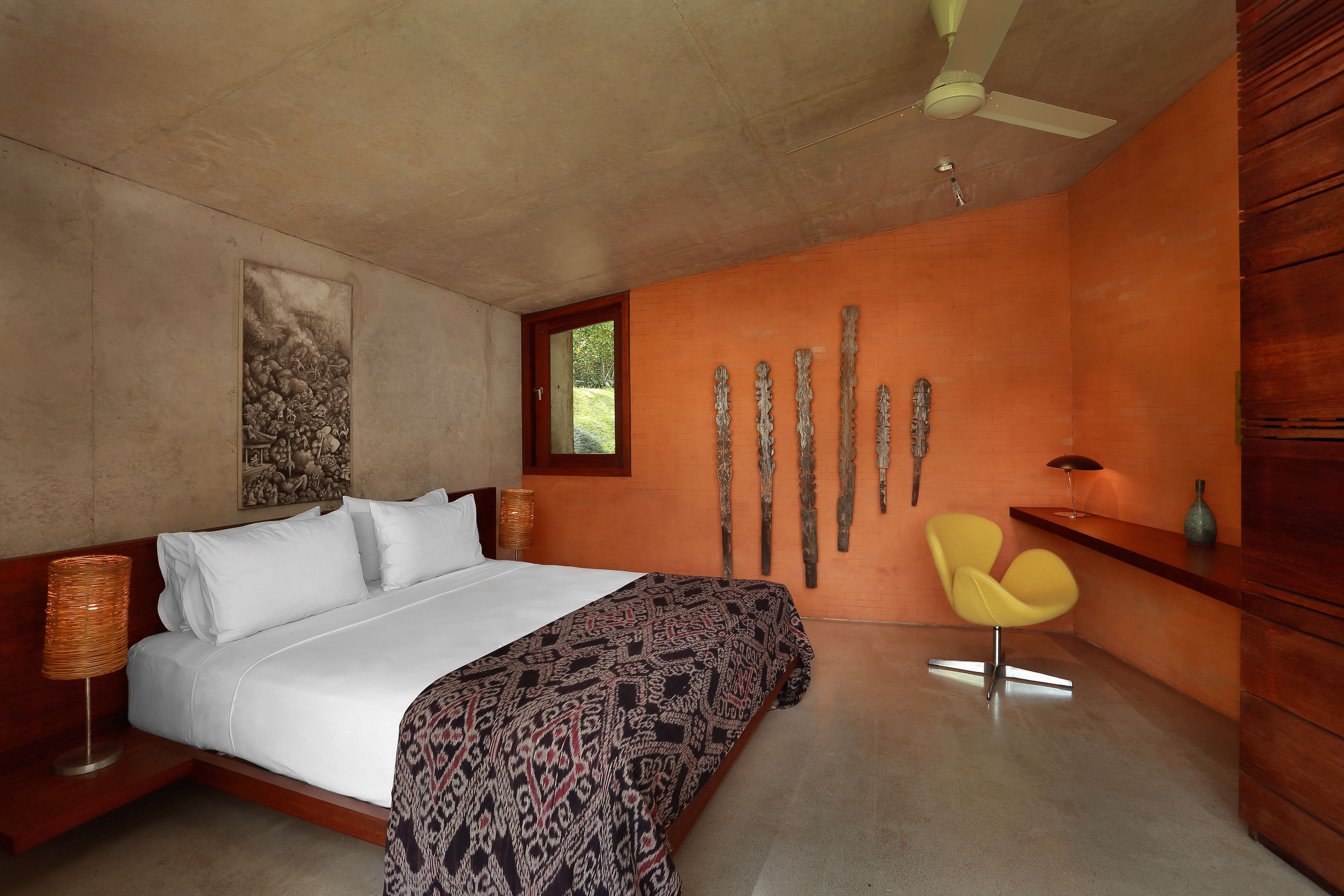 A modern bedroom with a large bed, a wooden headboard, a yellow chair, and a unique wall art piece.