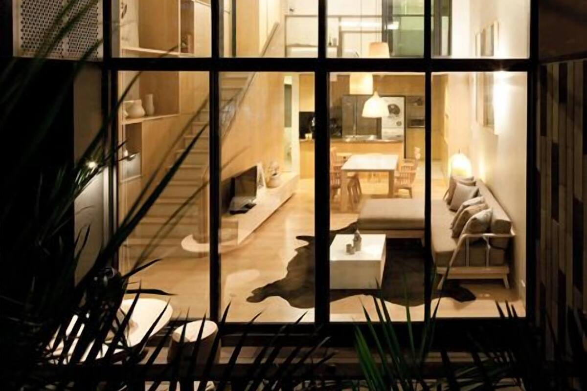 A modern interior with a staircase leading to a dining area, a kitchen, and a living space with a sofa and coffee table.