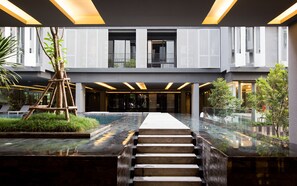 Ein modernes Gebäude mit einer zentralen Treppe, einem Pool und einem Glasgeländer.
