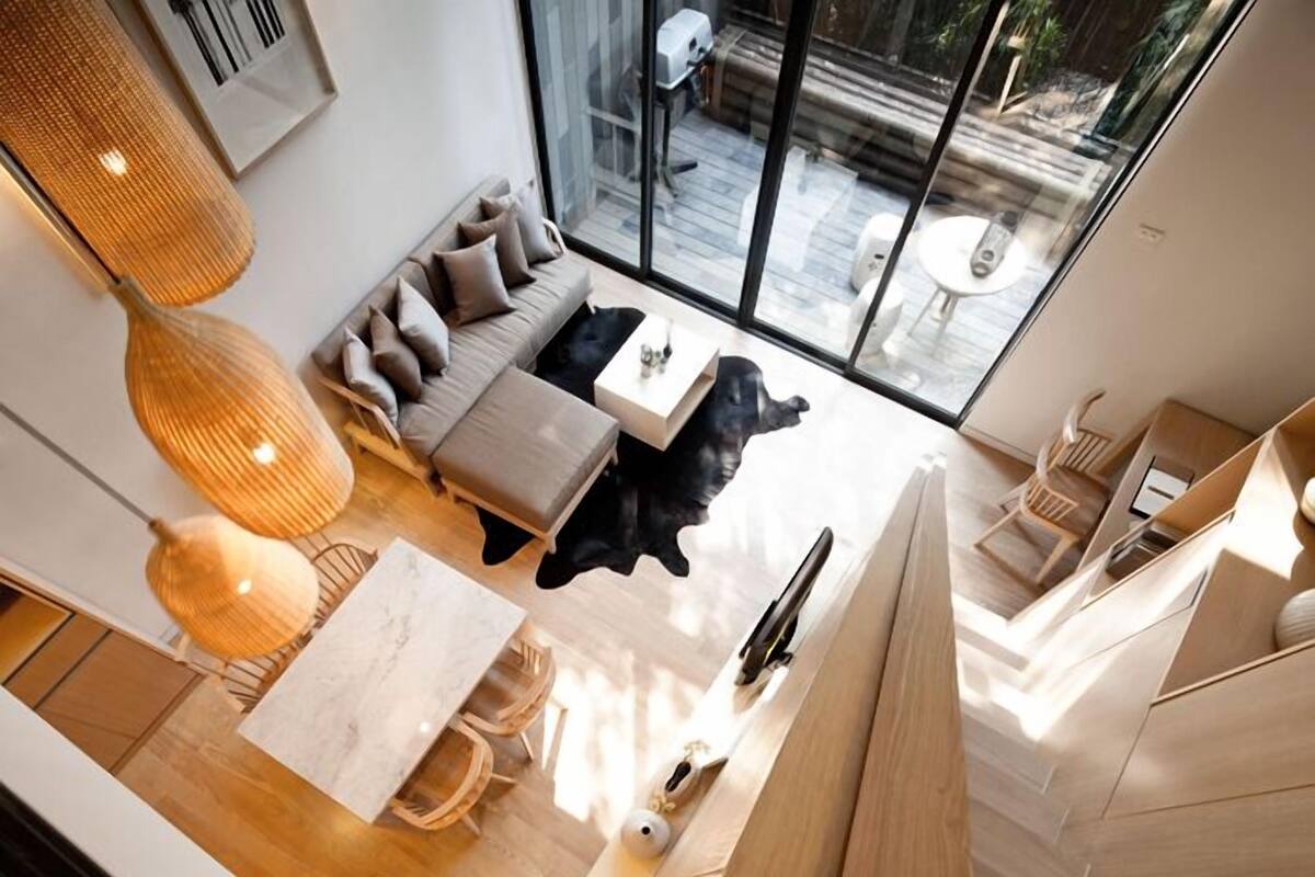 A modern living room with a sofa, coffee table, and a black dog.