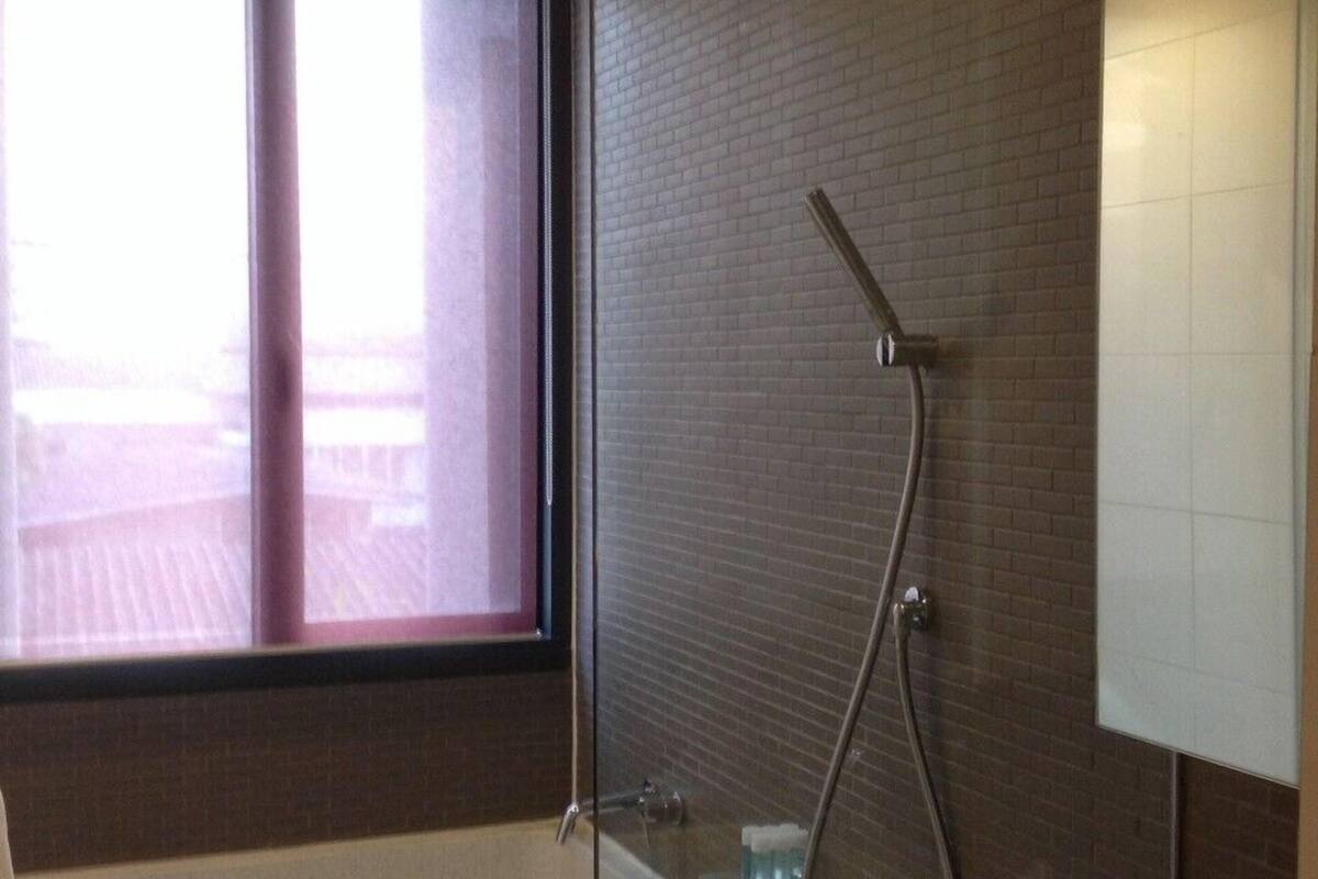 A modern bathroom with a glass-enclosed shower, a bathtub, and a large window.