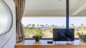 A modern room with a large window, a wooden desk, a flat-screen TV, and a potted plant. - Southern Sun Homestay North (Hengchun)