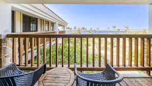 A balcony with wooden railings, two black chairs, and a view of the beach and ocean. - Southern Sun Homestay North (Hengchun)