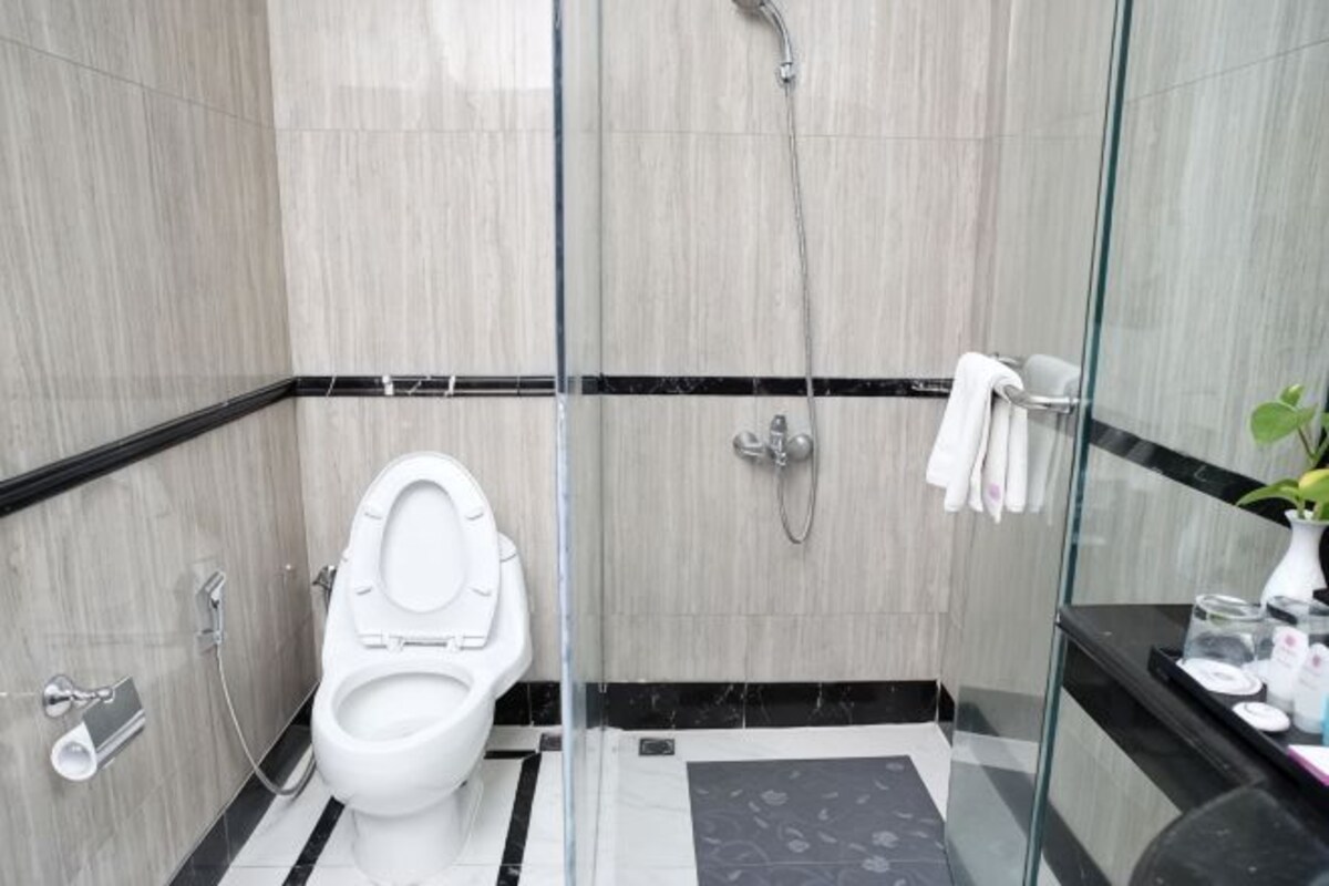 Ein modernes Badezimmer mit einer gläsernen Duschkabine, einer weißen Toilette und einem schwarz-weißen Fliesenboden.
