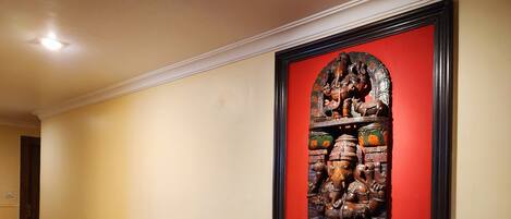 A hallway with a framed sculpture of a deity on a dark wooden table.