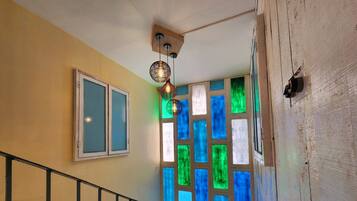 Eine Treppe mit Metallgeländer, ein Fenster mit satiniertem Glas und eine Wand mit farbenfrohen Glasfenstern.