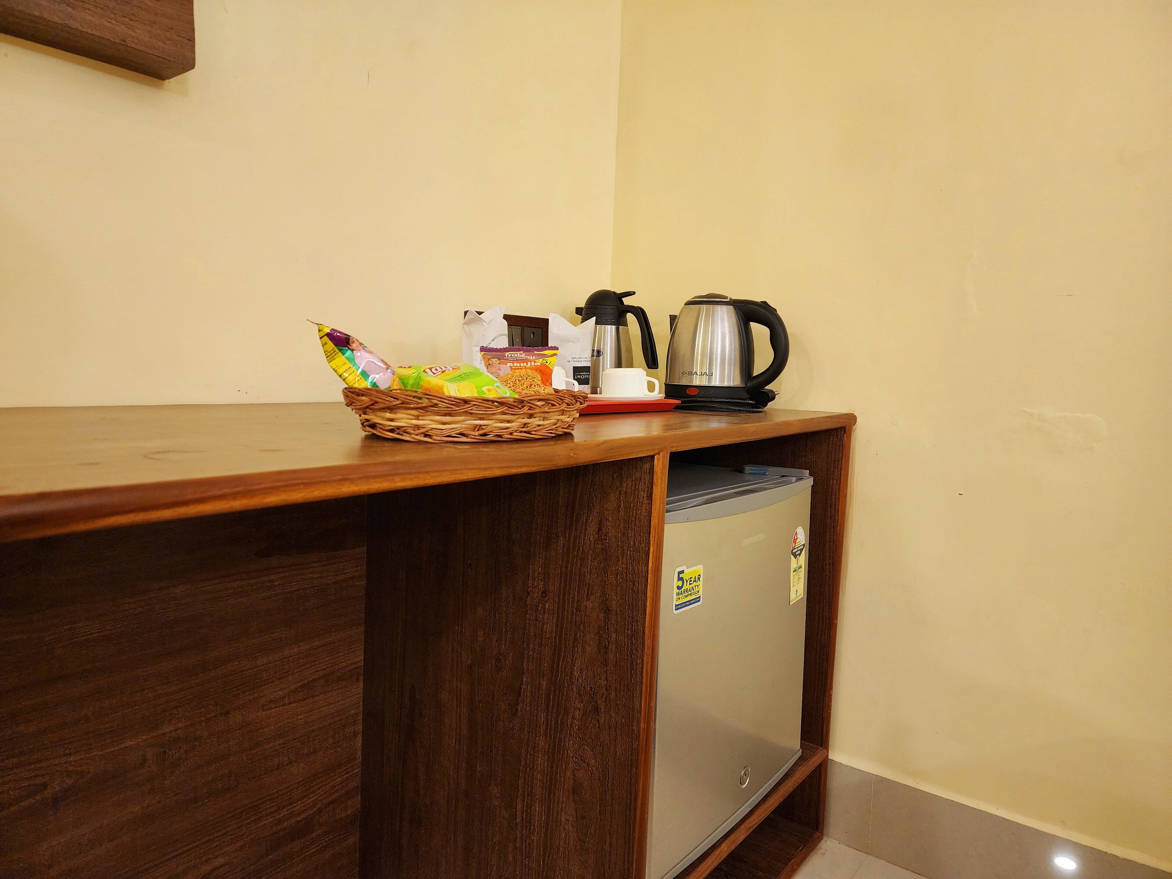 A kitchenette area with a wooden countertop, a stainless steel kettle, a coffee maker, and a basket of snacks.