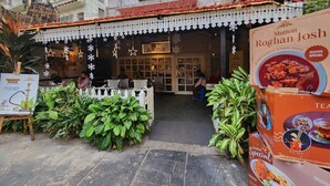 A restaurant with outdoor seating, a sign for 'Wise Owl Coffee Shop', and a festive decoration. - Wise Owl Comfotel (Kolkata)