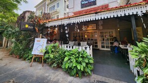 An outdoor seating area with tables and chairs, surrounded by potted plants. - Wise Owl Comfotel (Kolkata)