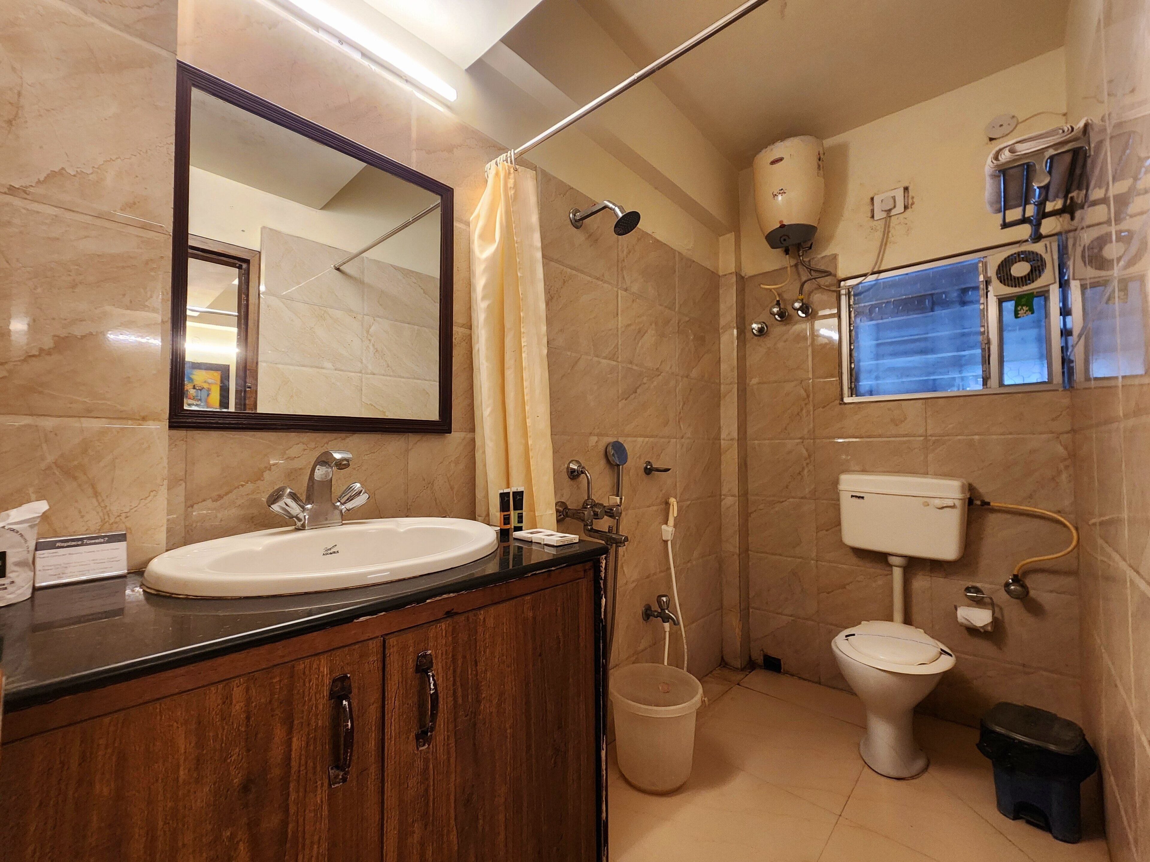 Ein Badezimmer mit Waschbecken, Spiegel, Dusche, Toilette und Mülleimer.