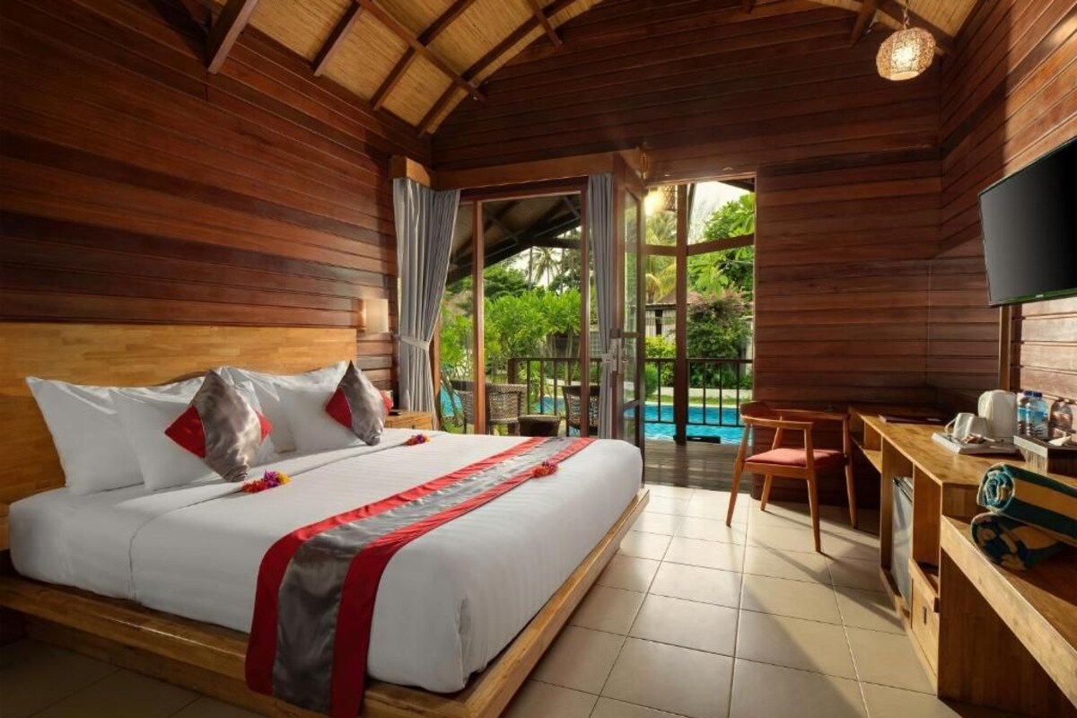 Quarto de madeira com uma cama, uma escrivaninha e vista para uma piscina.