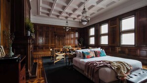 A room with a large bed, a desk, and a chair. There are windows and a chandelier. - The Old Clare by Ode Hotels (Chippendale)