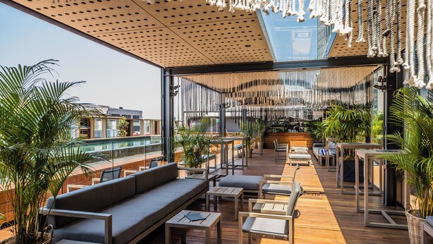 A rooftop bar with wooden flooring, seating arrangements, and hanging decorations. - The Old Clare by Ode Hotels (Chippendale)