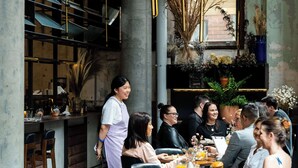 A restaurant with a bar area, wooden chairs, and a waiter serving guests. - The Old Clare by Ode Hotels (Chippendale)