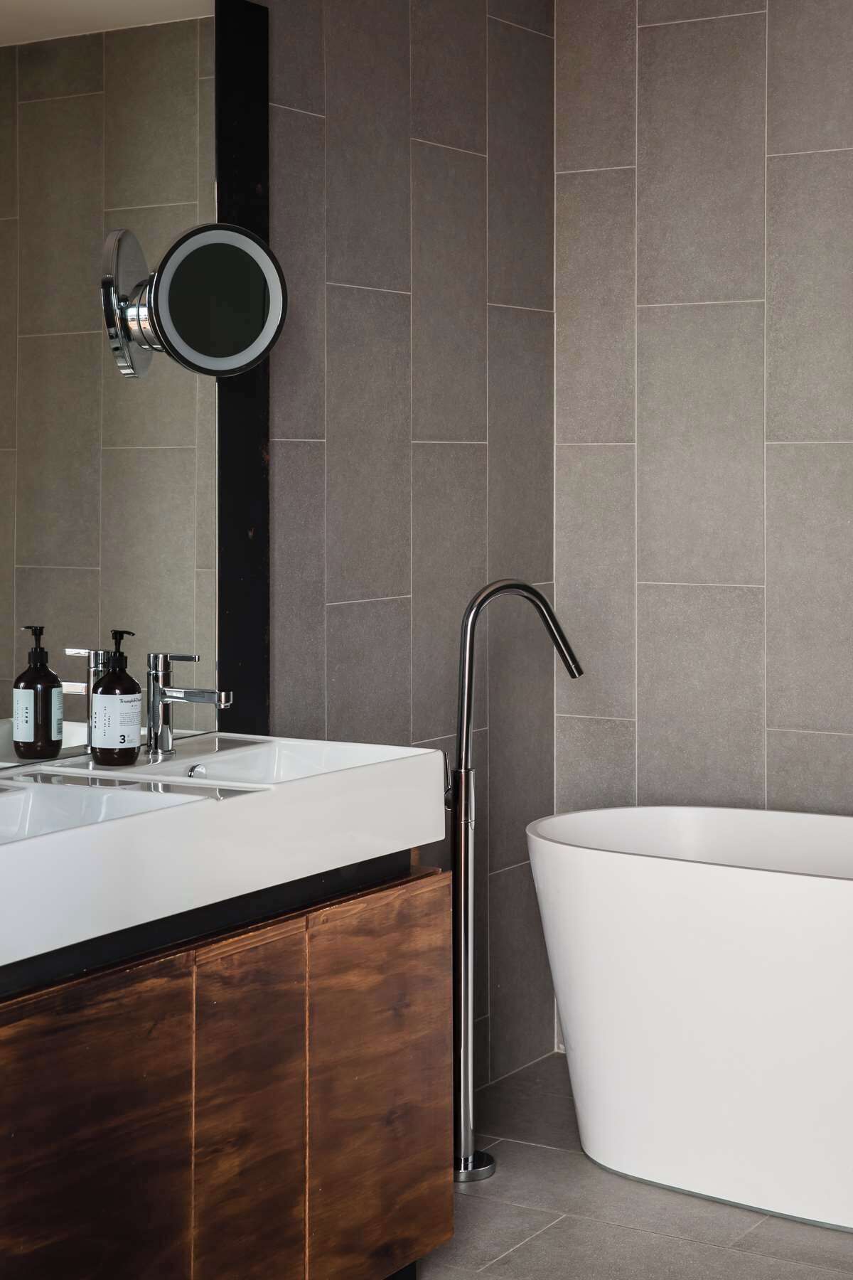 Un baño moderno con una bañera independiente, un tocador con espejo y dos botellas de champú.