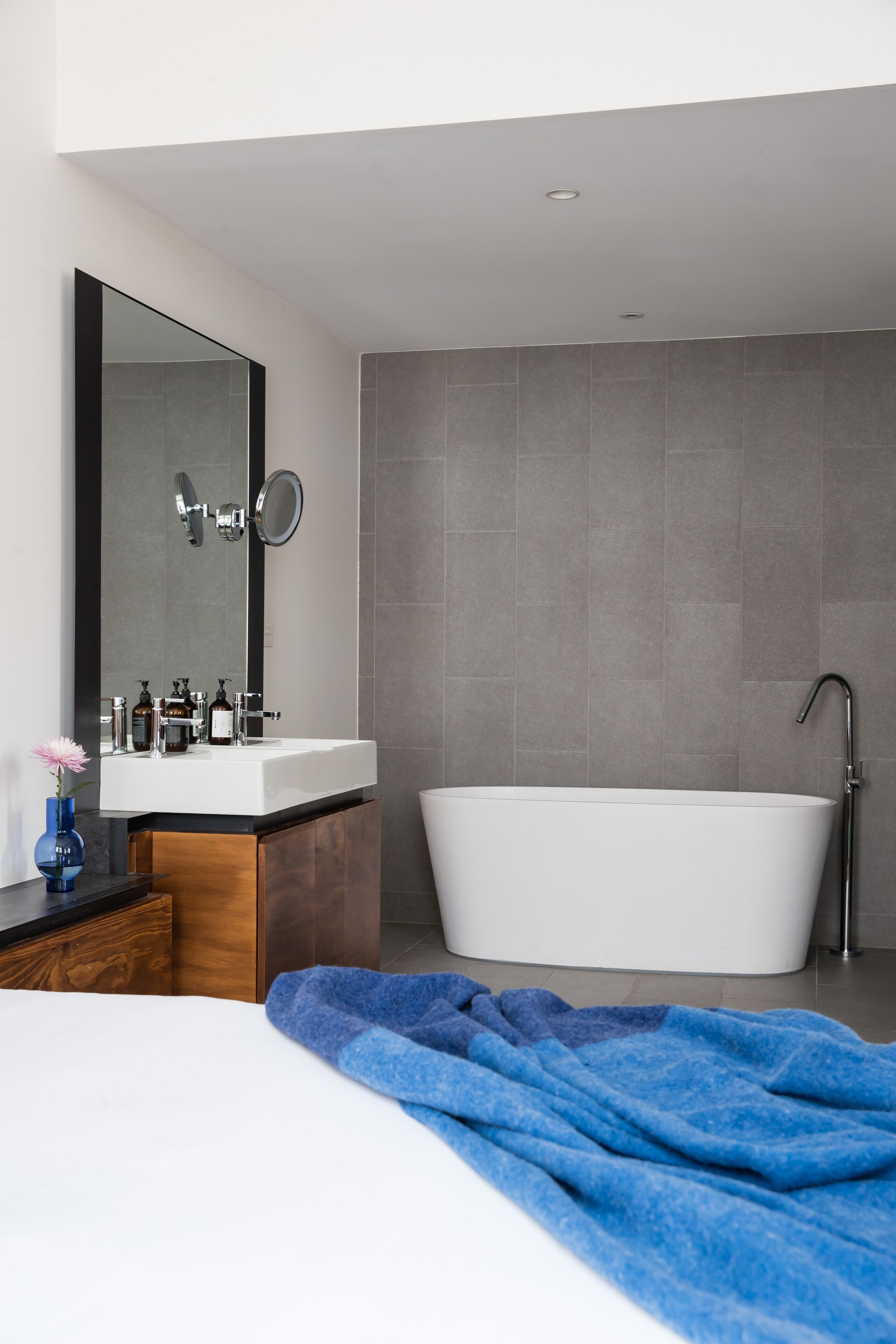 A modern bathroom with a white sink, a large mirror, and a freestanding bathtub.
