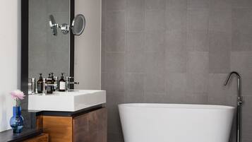 A modern bathroom with a white sink, a large mirror, and a freestanding bathtub.