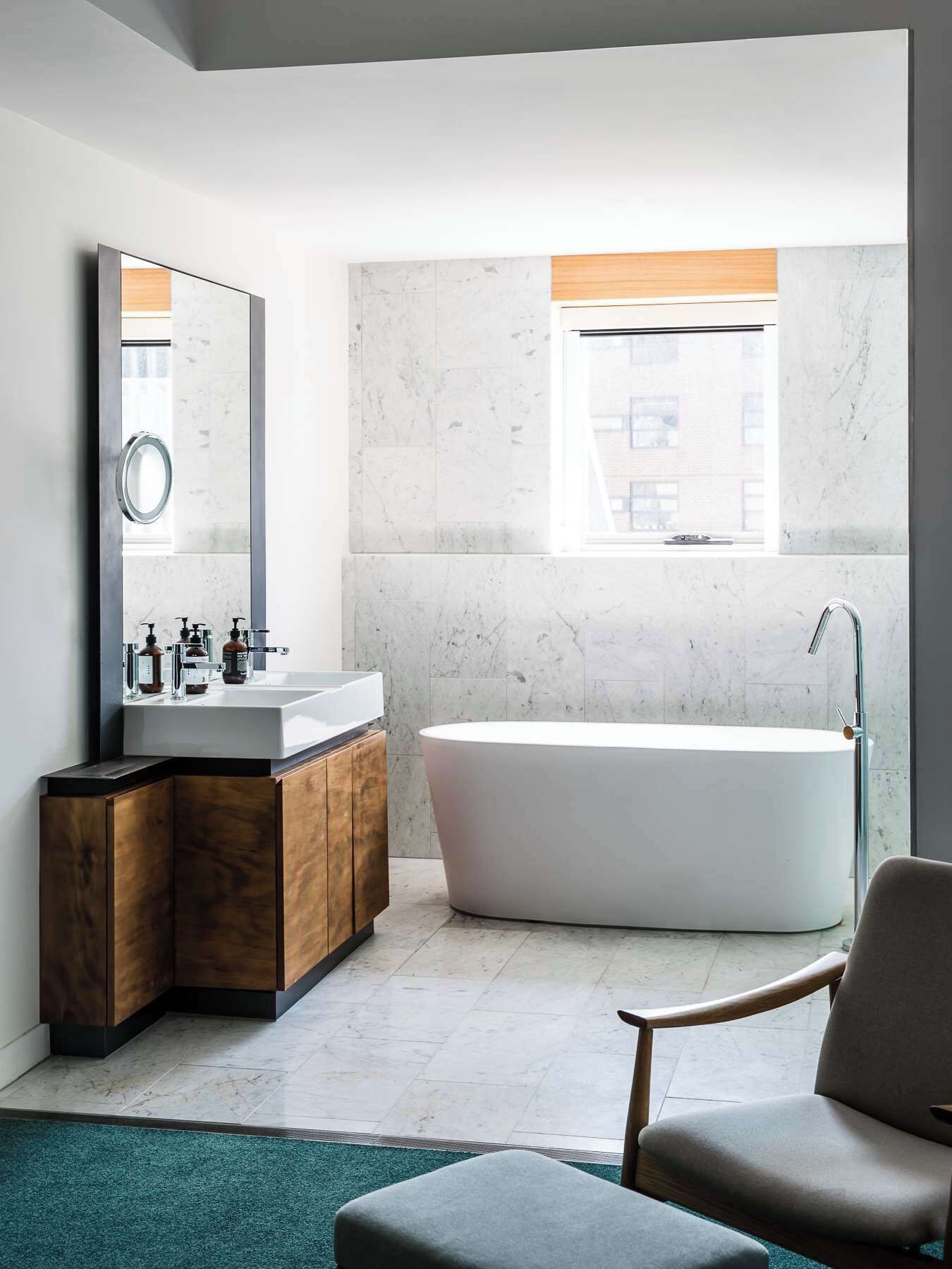 A modern bathroom with a freestanding bathtub, a large mirror, and a vanity with a wooden cabinet.