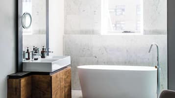 A modern bathroom with a freestanding bathtub, a large mirror, and a vanity with a wooden cabinet.