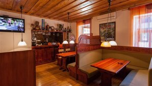 A cozy room with wooden furniture, a television, and a bar area. - SUNSET Hotel (Jurmala)