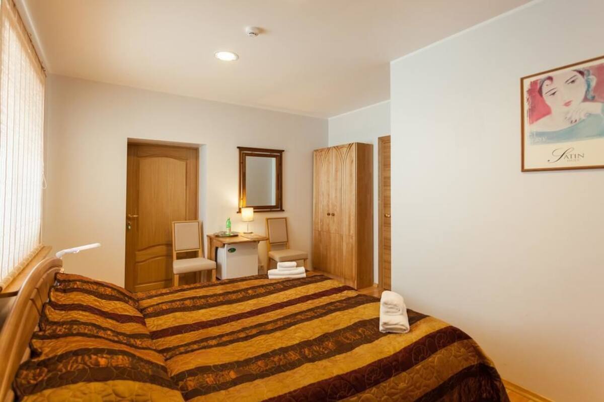 A hotel room with a bed, a desk, a chair, a wardrobe, and a bathroom door.