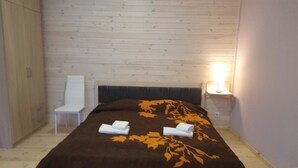 A room with a bed, a chair, and a nightstand with a lamp. - SUNSET Hotel (Jurmala)