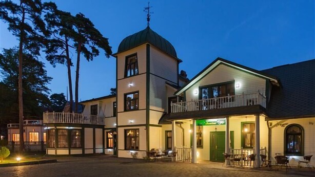 A building with a tower, a balcony, and a ground-level entrance. - SUNSET Hotel (Jurmala)