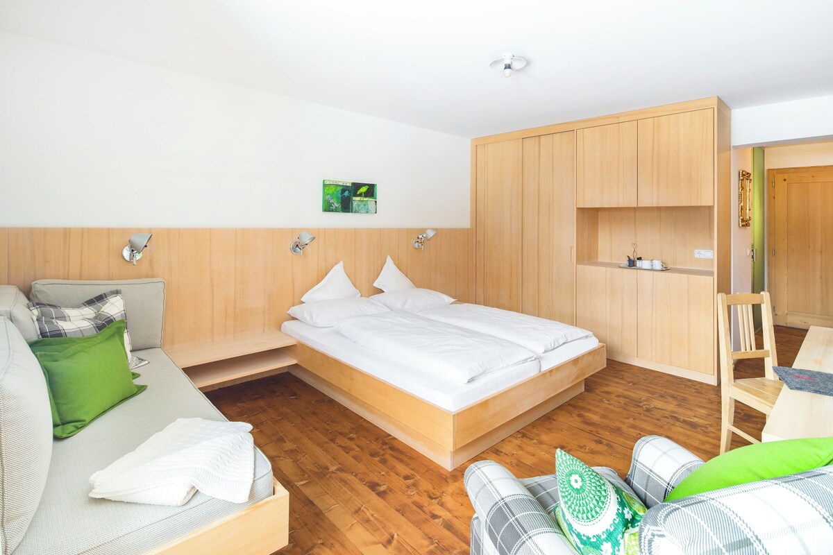 Quarto moderno com cama, sofá, escrivaninha e guarda-roupa.
