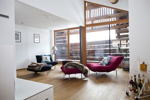 Uma sala de estar moderna com dois sofás, uma mesa de centro e um aparador de bebidas.