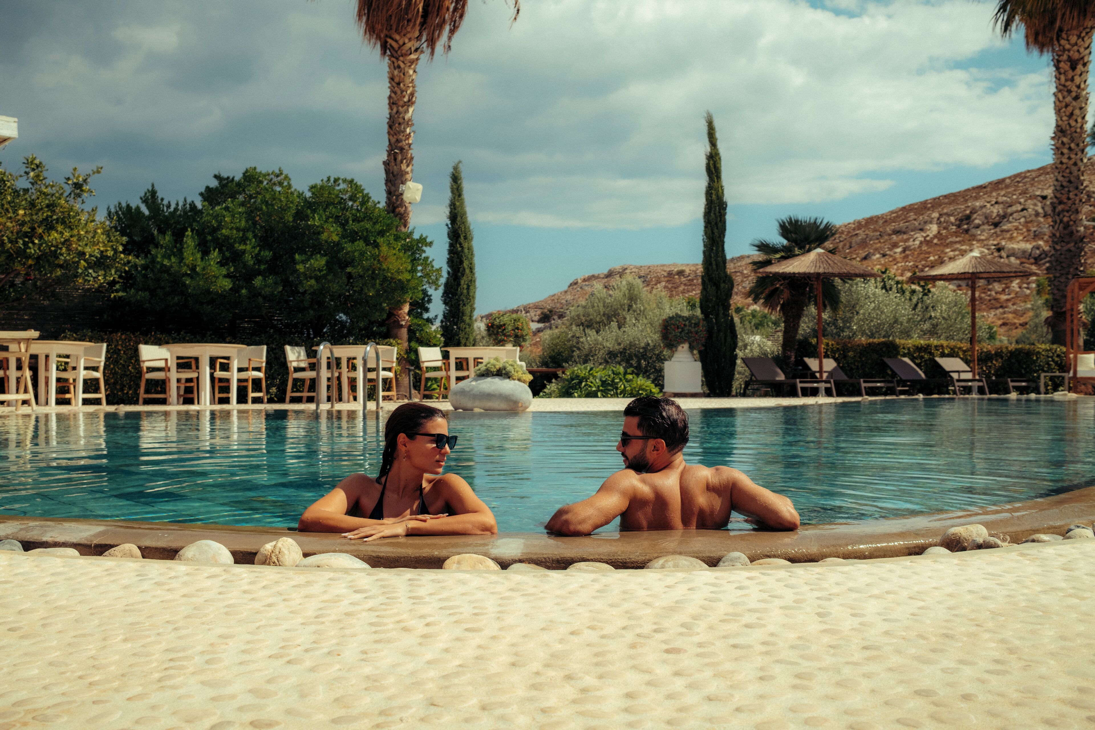 A pool area with lounge chairs and palm trees.
