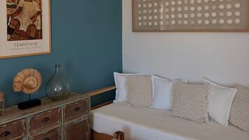 A room with a blue wall, a white sofa, a woven basket, a framed artwork, and a decorative panel.