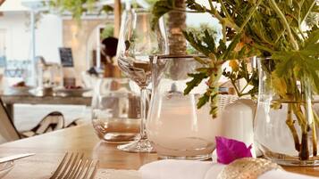 A table set with clear glassware, a lace tablecloth, and a vase with green foliage.