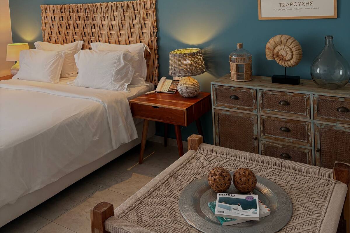 Een slaapkamer met een bed, nachtkastje, lamp, decoratieve accessoires en een lijst aan de muur.