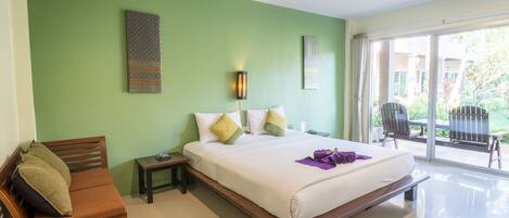 A bedroom with a bed, a wooden bench, a nightstand, and a view of the outside through a sliding glass door.