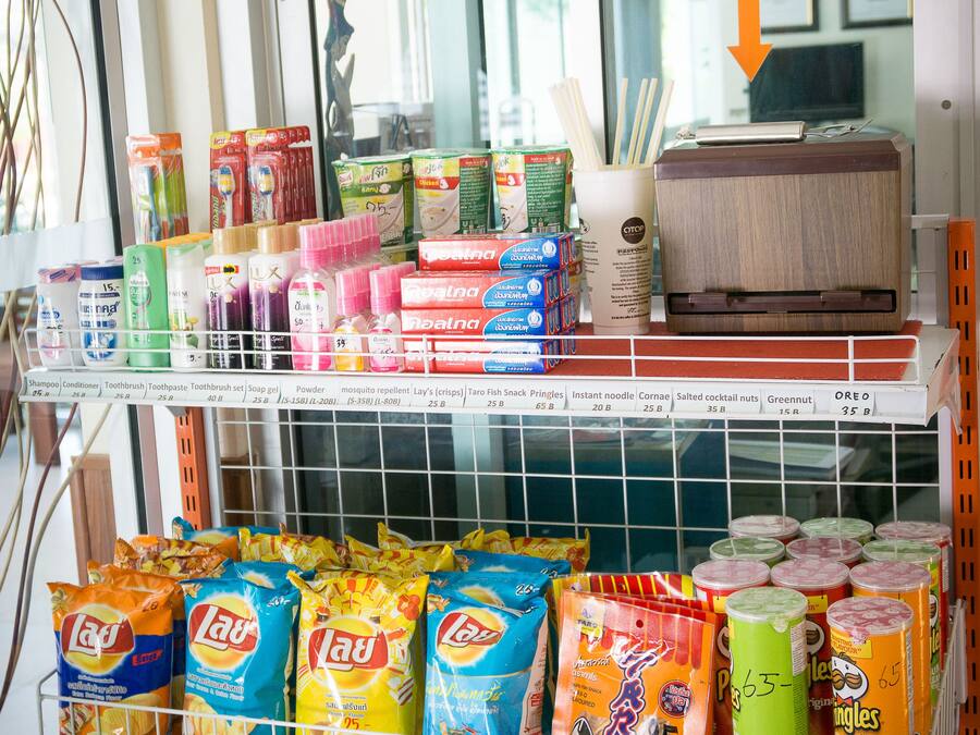 A self-service kiosk with a payment sign, stocked with various food items and household products.