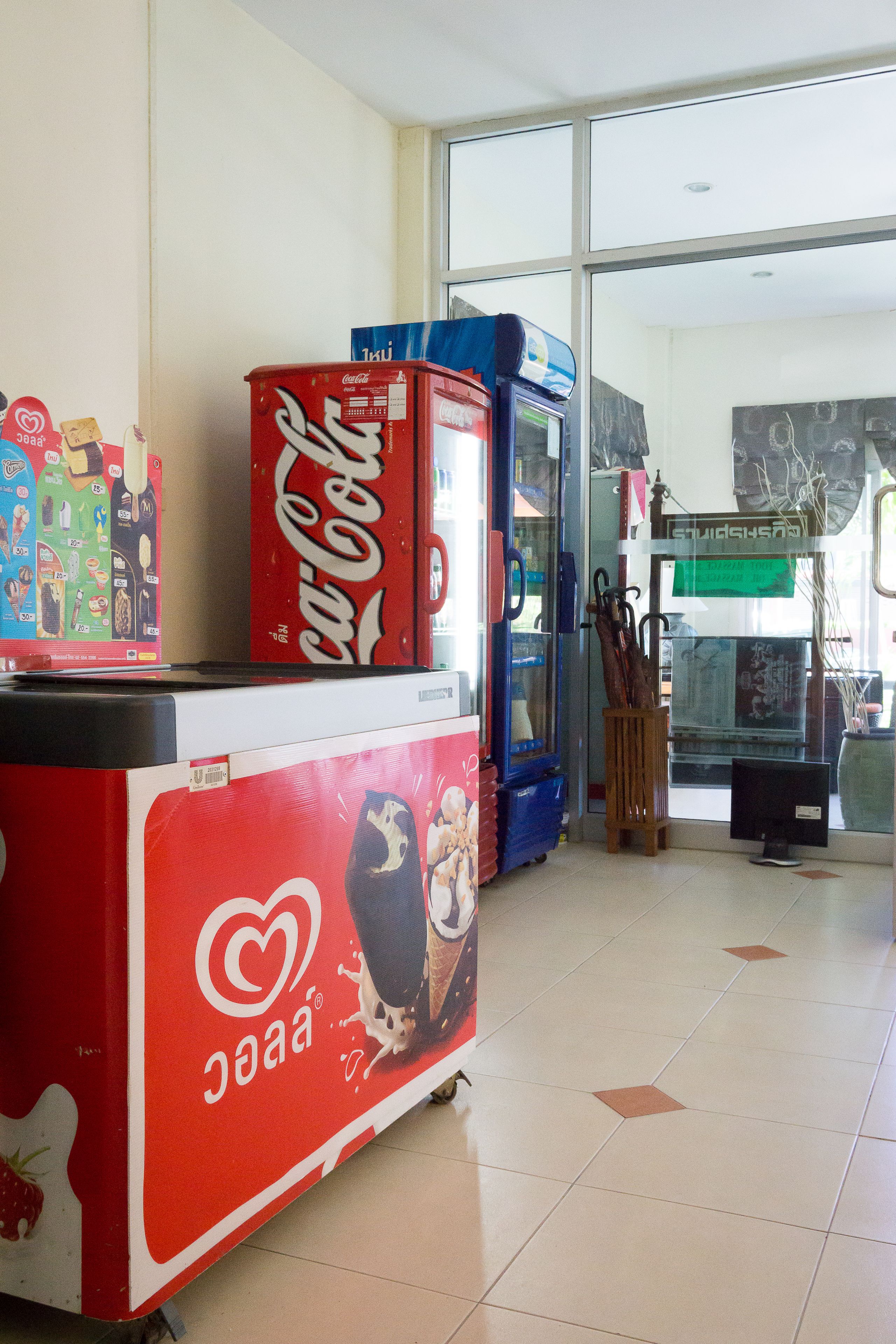 Zona de máquinas expendedoras con un refrigerador de Coca-Cola y una máquina expendedora azul.