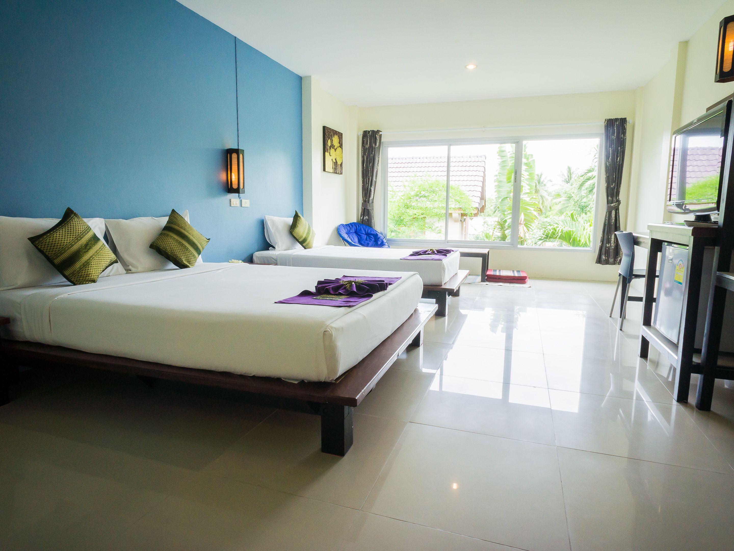 Habitación de hotel con dos camas, un escritorio y un ventanal grande con cortinas.