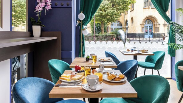 A dining area with a table set for breakfast, including bread, fruit, and a cup of coffee. - Hôtel Bristol Metz Centre Gare (Metz)