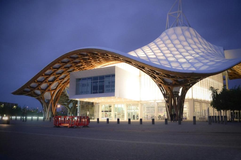 Un bâtiment moderne doté d’une structure de toit incurvée originale et d’une grande façade en verre.