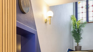 A staircase with dark blue steps, a wall-mounted clock, and a wall-mounted light fixture. - Hôtel Bristol Metz Centre Gare (Metz)