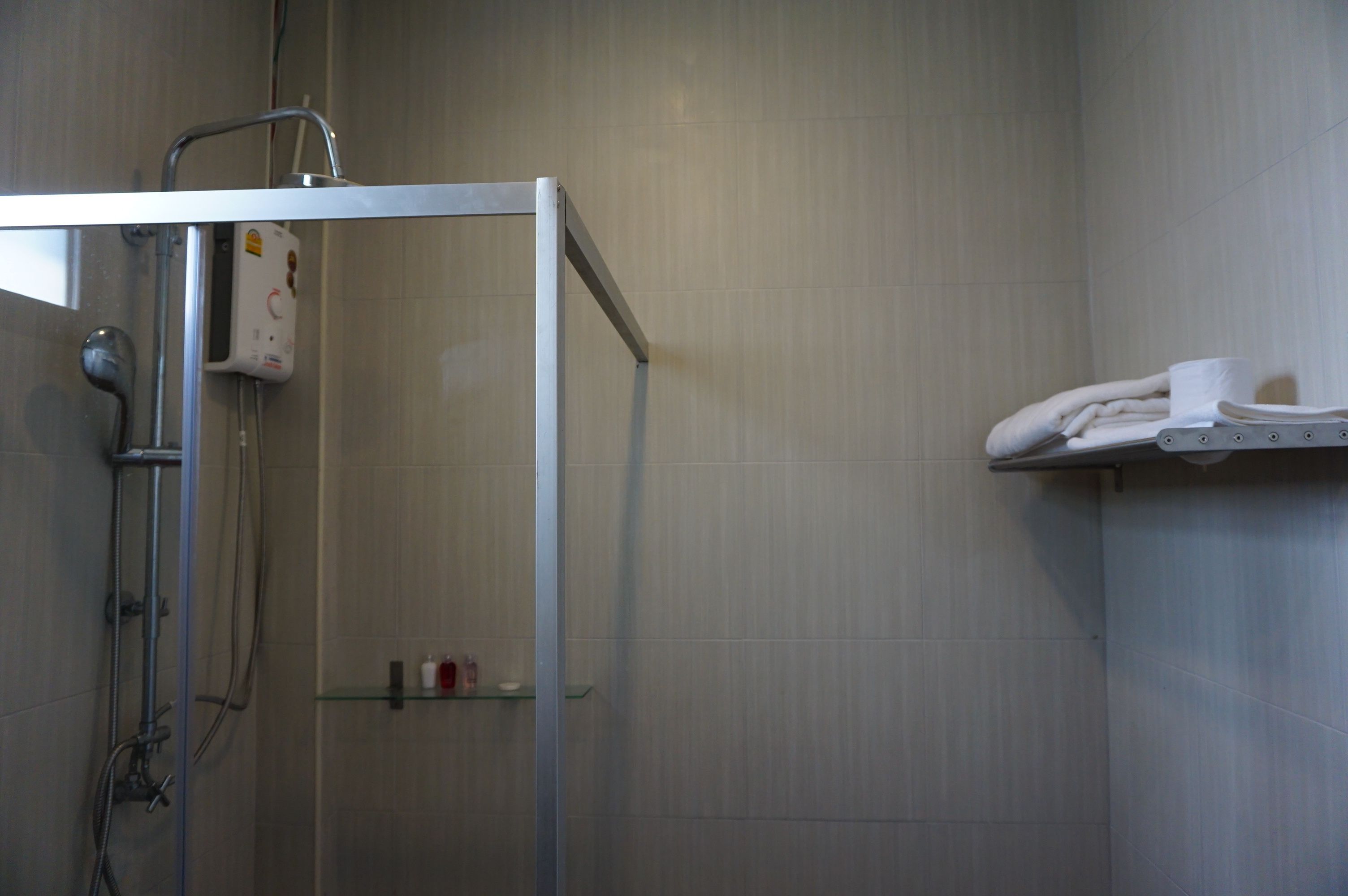 Una ducha con puerta de cristal, un perchero con toallas dobladas y un estante con artículos de tocador.
