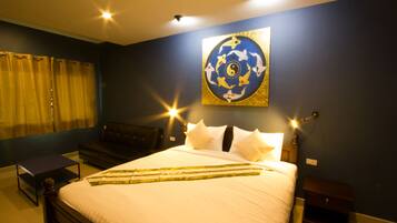 A neatly made bed with white linens, a headboard, and a bedside table with a lamp.